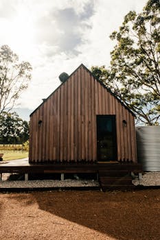 Charming wooden cabin surrounded by lush trees in a rural outdoor landscape.