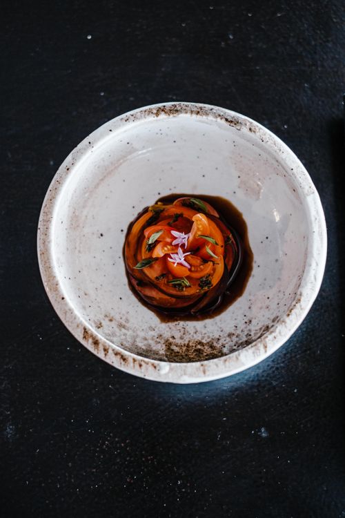 Free Elegant tomato salad elegantly presented in a ceramic bowl with soy sauce accent. Stock Photo