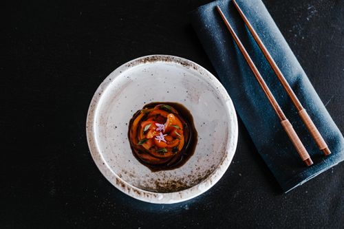 Free Close-up of an Asian appetizer in a bowl with chopsticks on a dark background. Stock Photo
