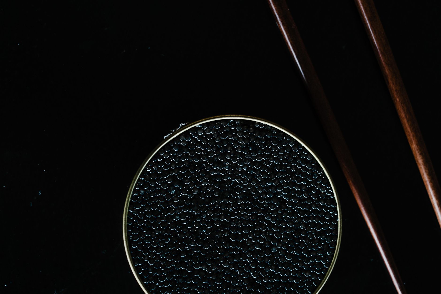 Elegant black caviar dish with chopsticks on a dark background, ideal for gourmet or luxury food themes.