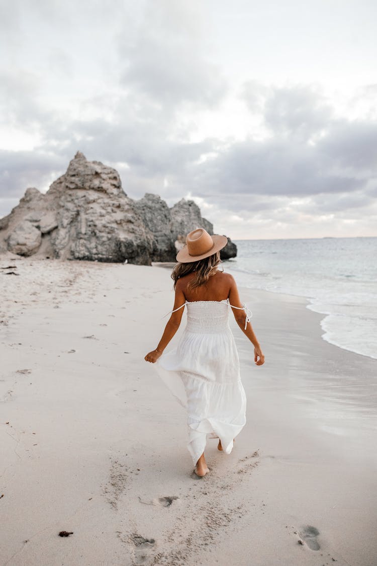 Woman In White Spaghetti Strap Dress Walking On Beach