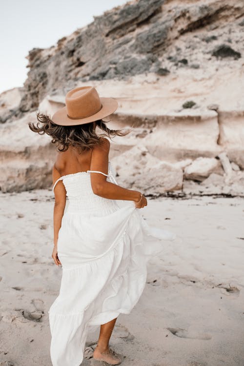 Woman in White Dress Wearing a Hat at the Beach