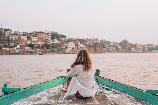Woman sitting on a boat enjoying the tranquil view of Varanasi cityscape.