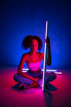 Creative portrait of a woman sitting with neon lights, showcasing vibrant colors and modern style.