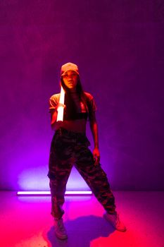 Stylish Gen Z woman posing under vibrant purple fluorescent lights in streetwear.