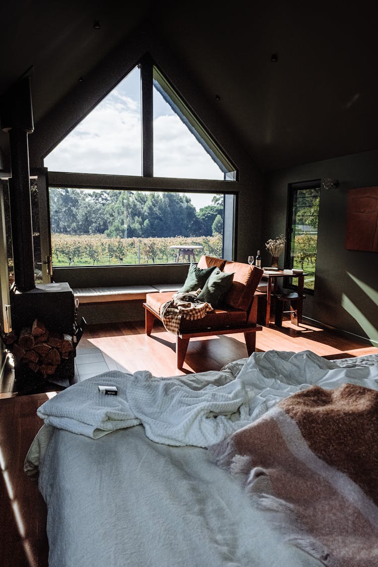 A Messy Bed In A Bedroom With A Big Window