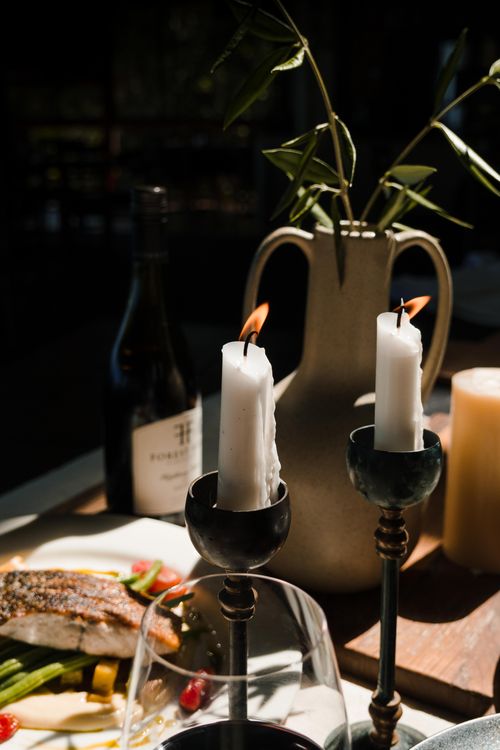 Free Cozy dinner setting with candles, wine, and a vase of greenery, perfect for romantic ambiance. Stock Photo