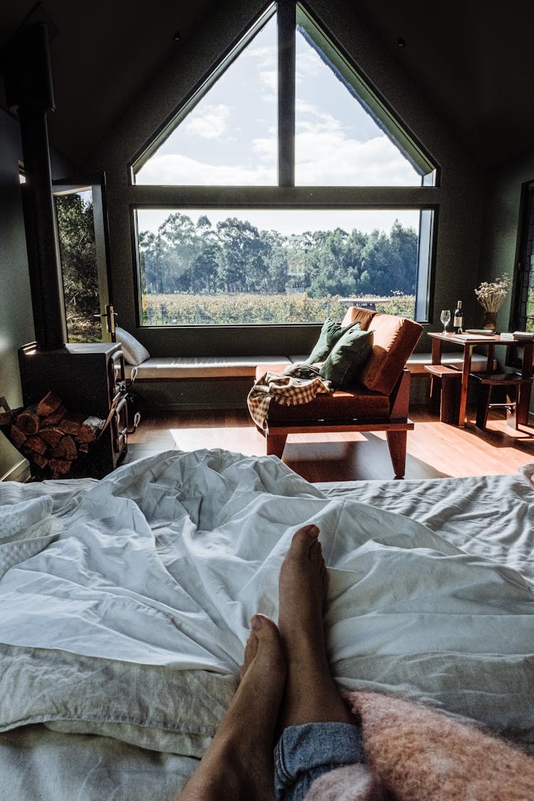 A Messy Bed In A Bedroom With A Big Window