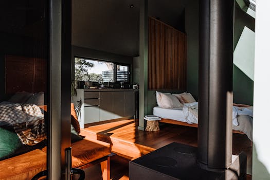 A modern cabin interior featuring wooden floors, cozy furniture, and abundant natural light.