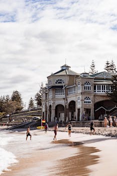 Sunlit view of Cottesloe Beach with the iconic Indiana Tea House and people enjoying the summer day.