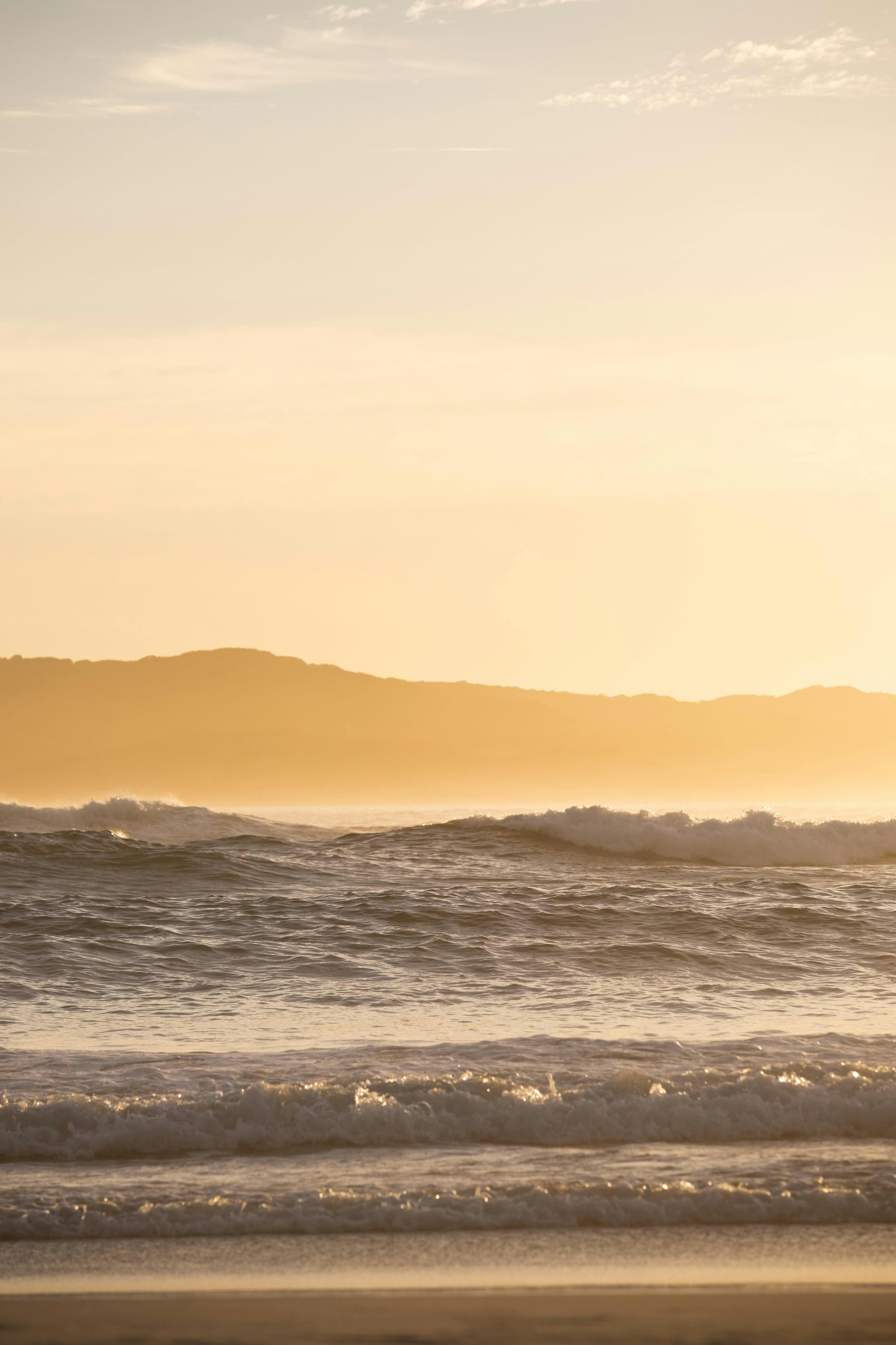 日出时海浪的宁静景色，背景是山丘的轮廓