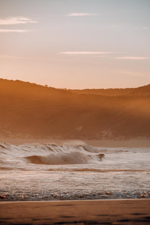 Free Sea Waves Crashing on the Shore during Sunset Stock Photo
