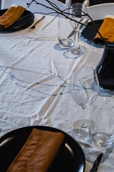 Minimalist table arrangement with black dishes, wine glasses, and earthy tones.