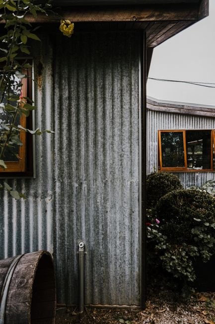 Photo by Rachel Claire on Pexels An old rustic bungalow with corrugated metal siding and wooden windows.