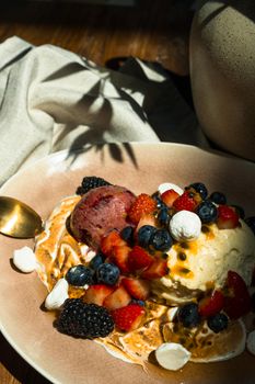 A close-up of a delicious ice cream dessert topped with fresh berries and drizzle.