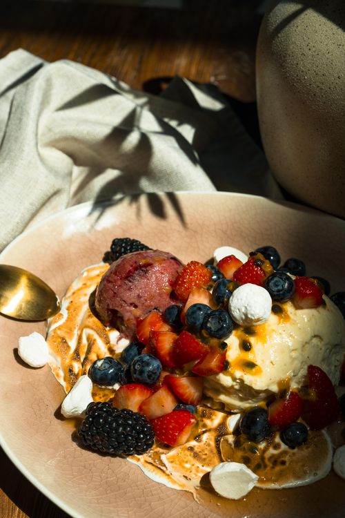 Free A close-up of a delicious ice cream dessert topped with fresh berries and drizzle. Stock Photo