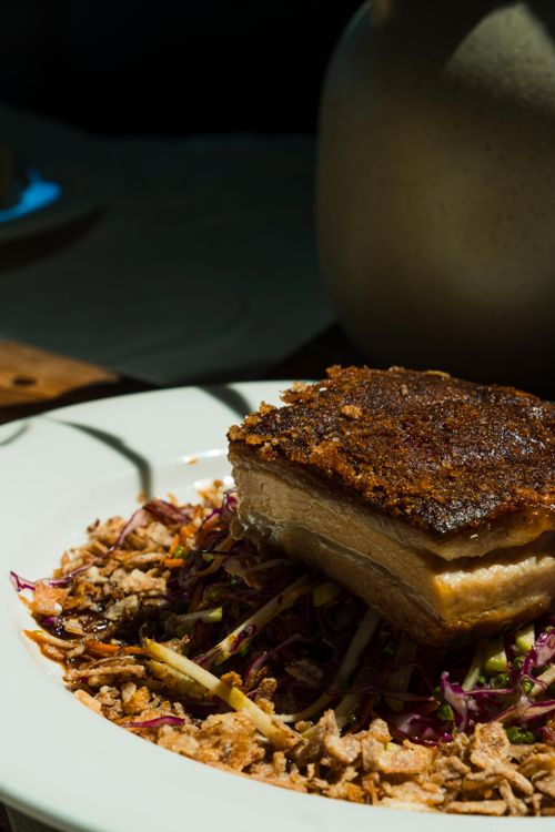 Free Delicious crispy pork belly on a bed of fresh gourmet salad, perfect for a hearty meal. Stock Photo