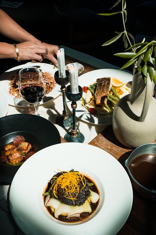 Food and Wine near Wax Candles and Plant in Vase