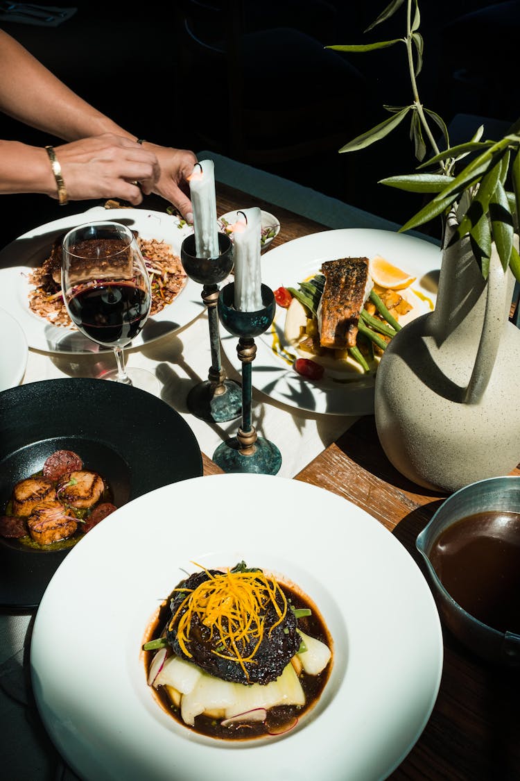 Food And Wine Near Wax Candles And Plant In Vase