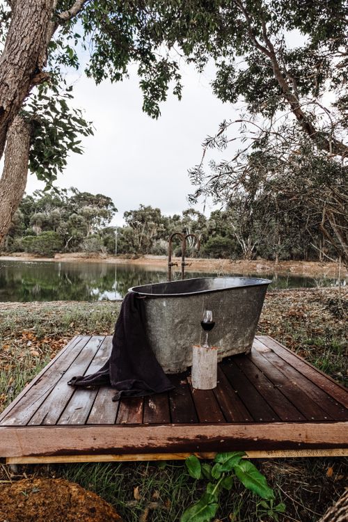 Free A vintage metal bathtub set by a peaceful lake surrounded by trees, offering a tranquil outdoor experience. Stock Photo