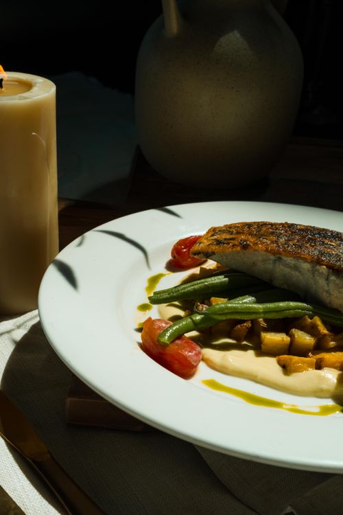 Free Delicious seafood plate featuring fish, green beans, and creamy sauce with elegant lighting. Stock Photo