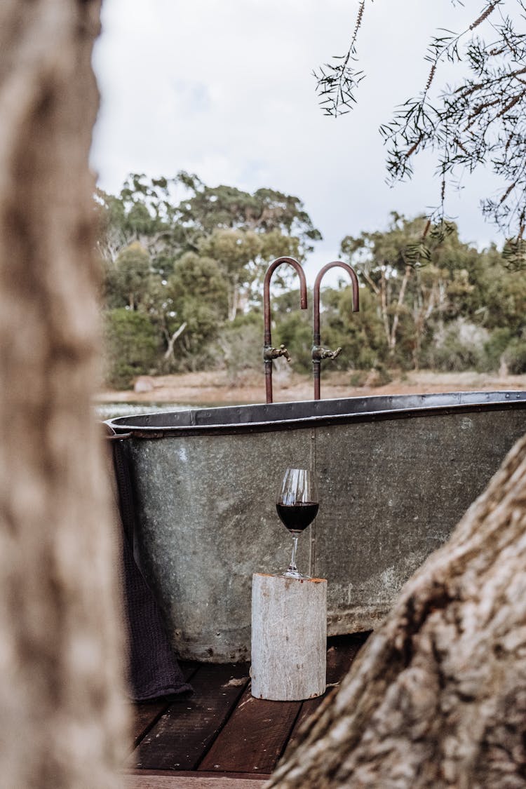 Photo Of A Glass Of Wine Beside A Metal Bathtub