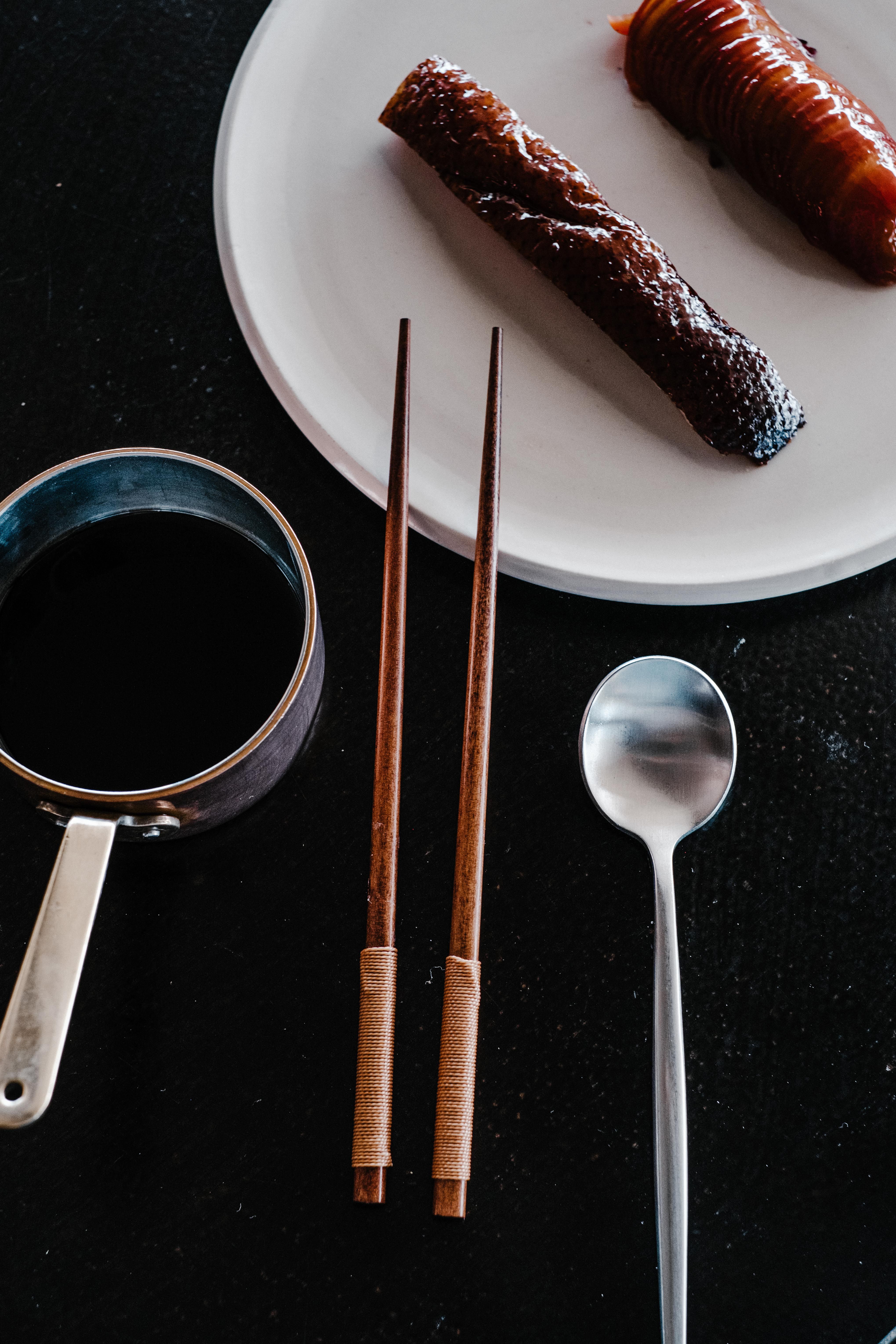 Flat lay image featuring chopsticks, salmon, and a spoon with a dark, moody aesthetic.