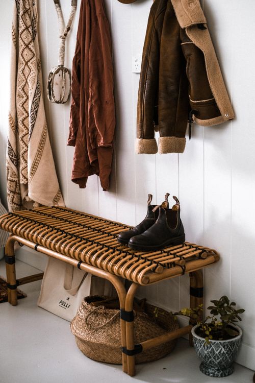 Free Warm and inviting entryway featuring a woven bench, hanging coats, and rustic decor on a white background. Stock Photo
