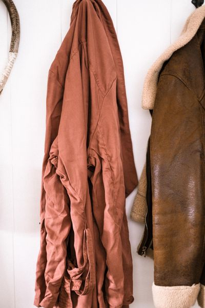 Rust silk coat and shearling jacket on a wall rail — photo by Rachel Claire on Pexels