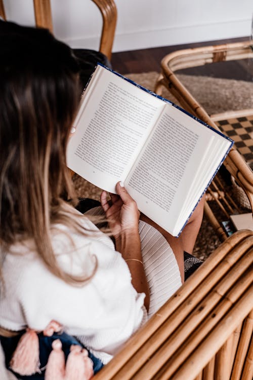 A Woman in White Sweater Reading a Book