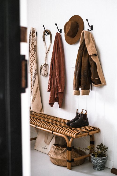 Free Stylish entryway decor with coats, hat, and boots on rattan bench. Stock Photo