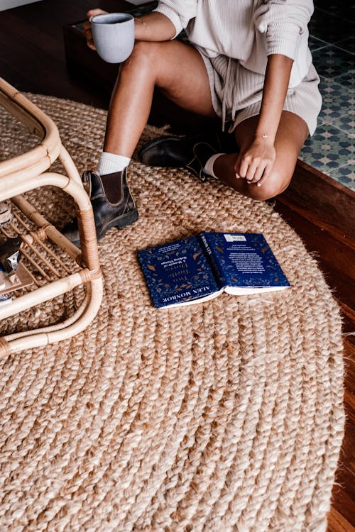 Person Holding a Cup of Coffee Sitting on the Floor