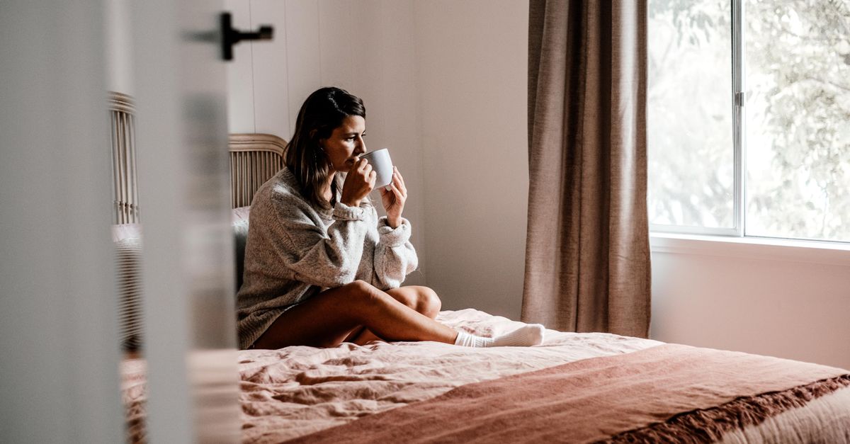 person sitting quietly by window with coffee at sunrise
