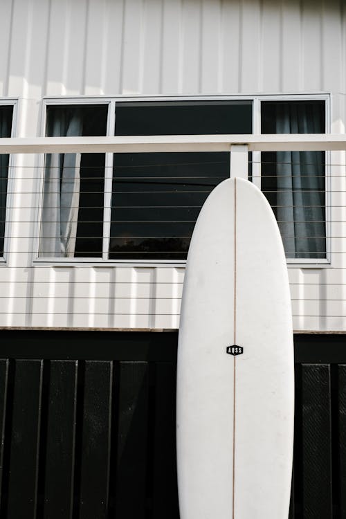 Photograph of a White Surfboard on a Black Gate