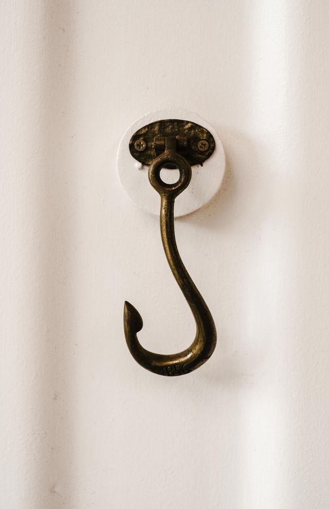 Antique brass wall hook mounted on a white wall — Rachel Claire on Pexels