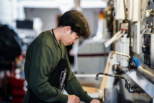 Free An Asian man wearing an apron works diligently in an industrial kitchen setting. Stock Photo