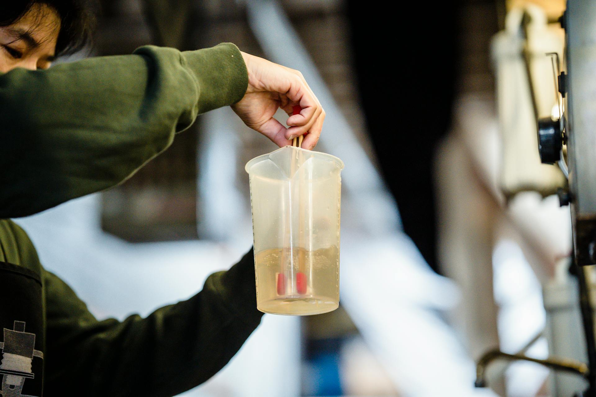 Photo of a Man in a Green Long Sleeve Shirt Mixing Liquid in a Measuring Cup