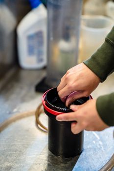 Close-up view of hands developing photographic film in a darkroom setting, showcasing a plastic container.