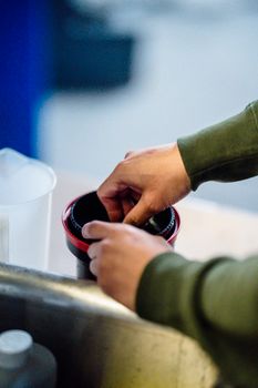 Close-up of hands developing film in a darkroom using a plastic container.