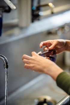 Close-up of hands washing photographic film under running water in a darkroom setting.