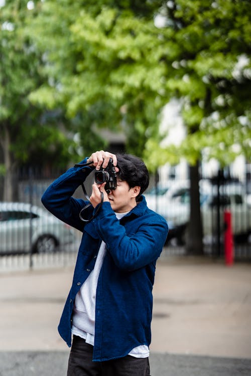 Man in Blue Jacket Using a Black Camera