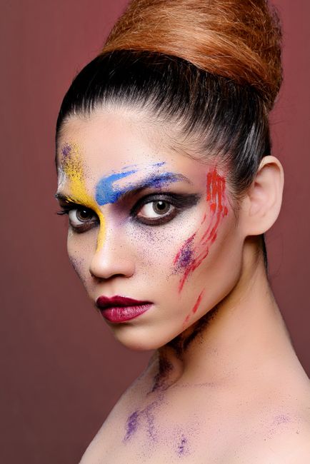 Stunning close-up portrait of a woman with vibrant artistic makeup, showcasing bold colors and intri