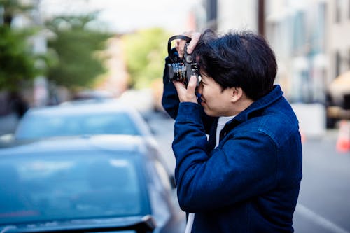 A Man in Blue Jacket Taking Photos in the Street