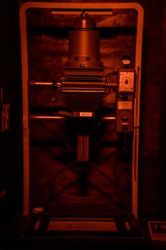 A classic film enlarger with vintage machinery in a dimly lit darkroom environment.