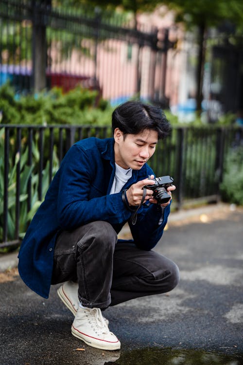Free A Man in Blue Long Sleeves Sitting on the Street while Looking at the Camera Stock Photo