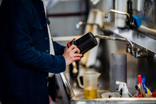 Close-up of hands processing film in a darkroom sink setup, showcasing equipment and tools.