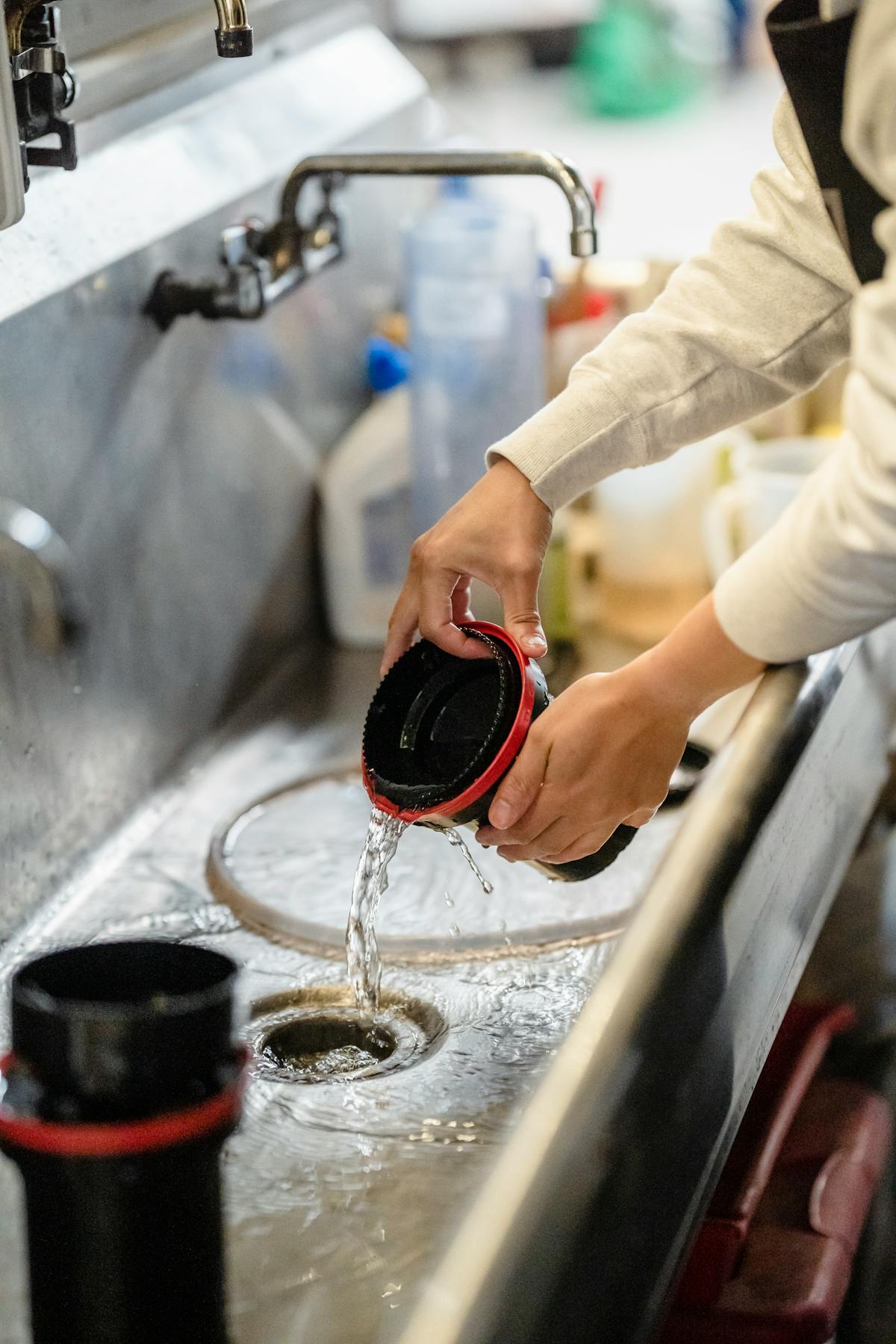 Persona che lava una tazza sopra il lavello con acqua corrente
