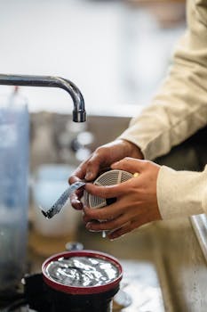 A person in a darkroom developing film at a sink with film reel in hand.