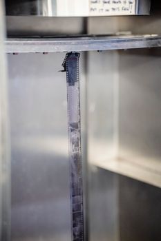 Close-up of an undeveloped film strip hanging in a classic darkroom. Perfect for analog photography enthusiasts.