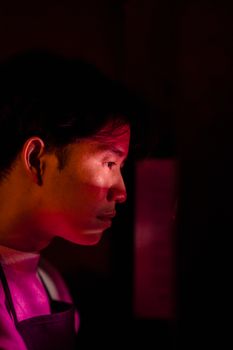 Side profile of a man in red light, creating a dramatic and mysterious mood.